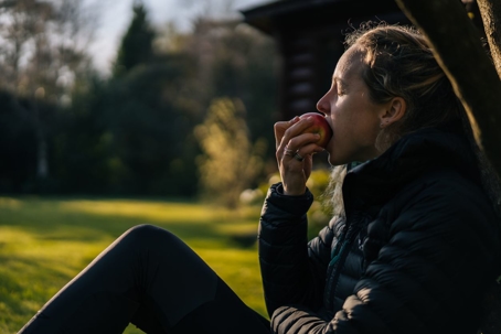 Woman eating an apple outdoors.