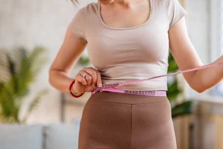 Woman measuring her waist to see how much weight she lost.